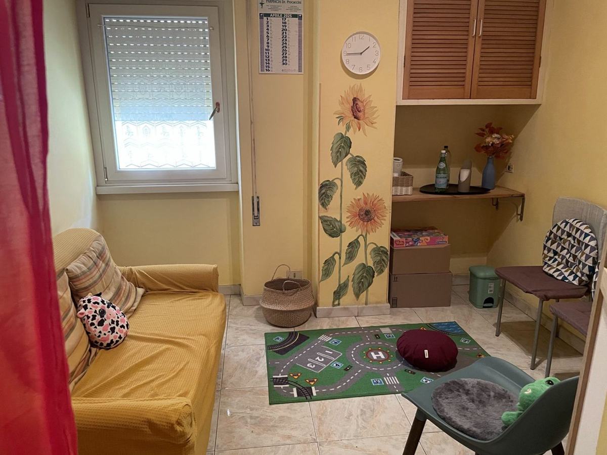 Studio per la valutazione DSA a Roma: la stanza con divano giallo, tappeto gioco e girasoli dipinti sulla parete